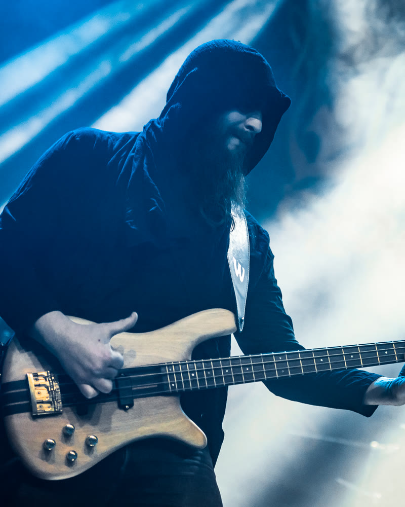 Maschi in a hood, backlit, playing the bass