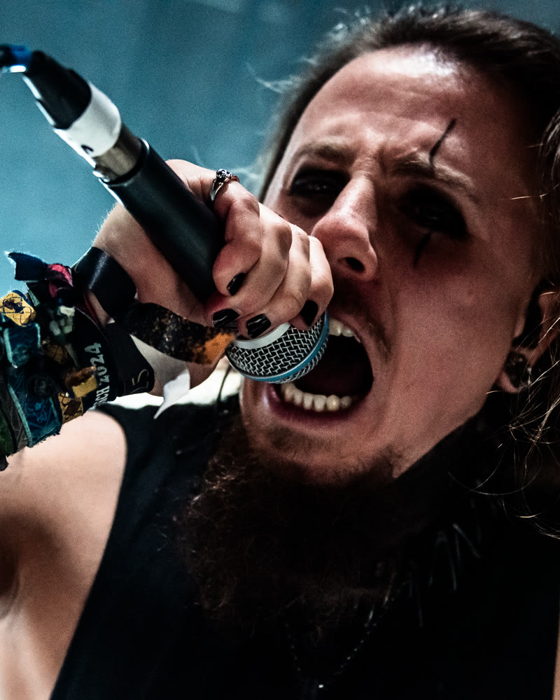 Simon at the microphone, head thrown back mid-scream, black face paint